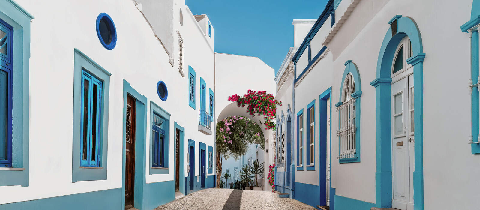 Straße in Olhão mit weißen und blauen Häusern und typisch portugiesischem Pflaster © Armando Oliveira - stock.adobe.com