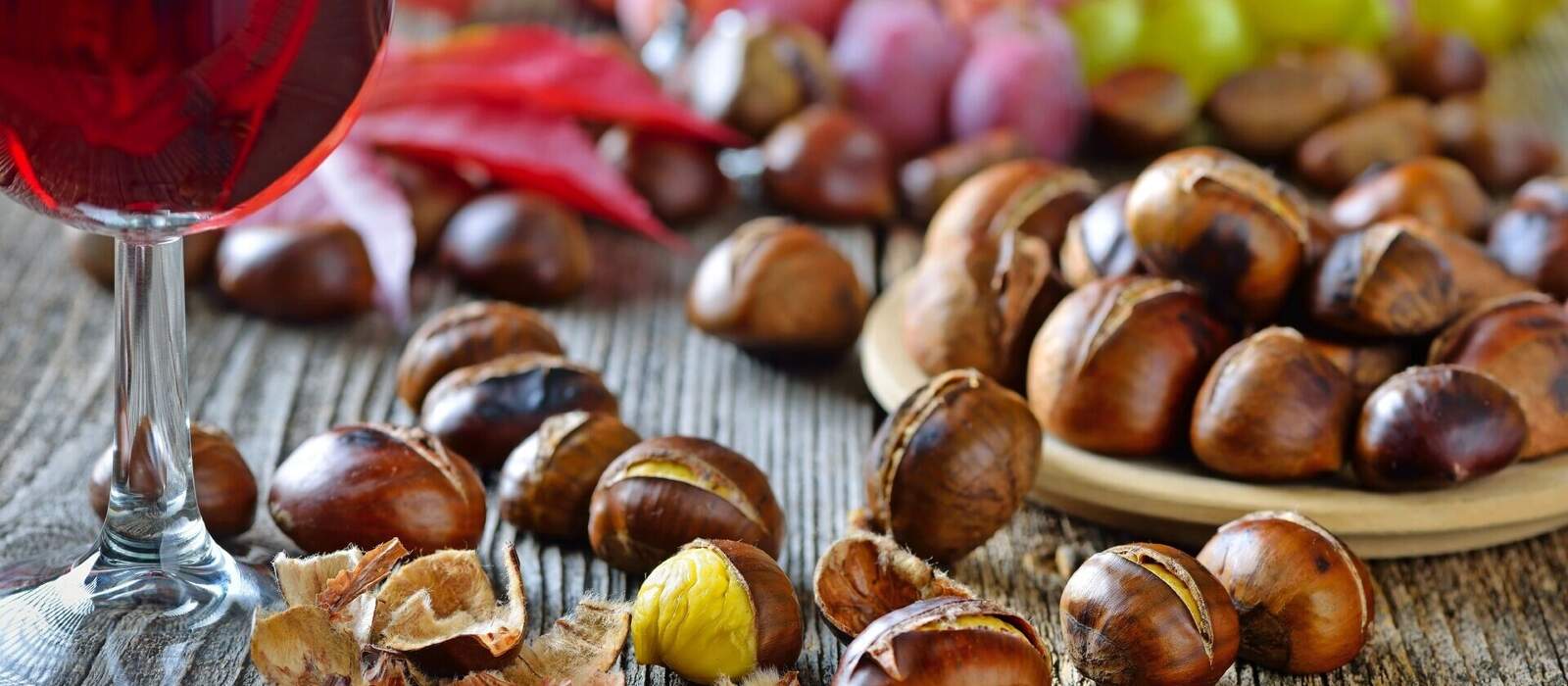 Geröstete Maroni mit neuem Rotwein, weiße und rote Weintrauben im Hintergrund © kab-vision - stock.adobe.com