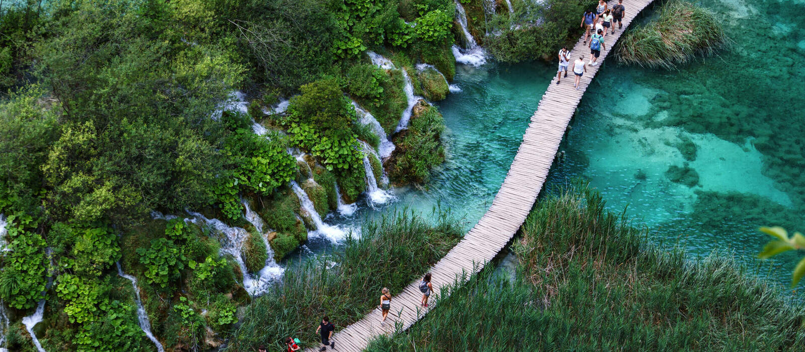 Luftaufnahme eines hölzernen Wanderwegs neben Wasserfällen im Nationalpark Plitvicer Seen © Sebastian - stock.adobe.com