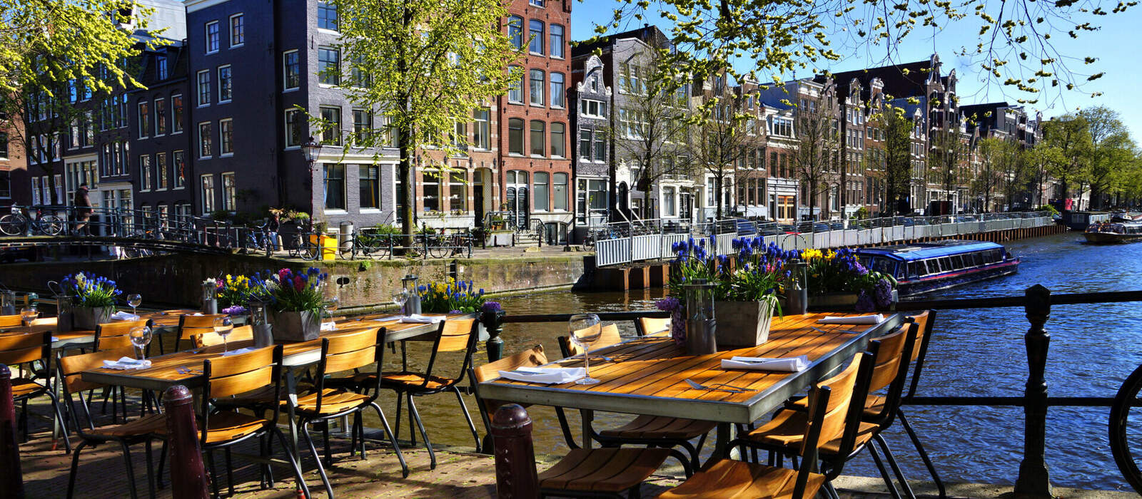 Restauranttische entlang der wunderschönen Grachten von Amsterdam unter blauem Himmel im Frühling © Jenifoto - stock.adobe.com